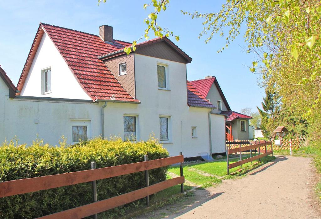 朱列斯拉赫Ferienwohnung Breege RUeG 1951的白色的房子,有红色的屋顶和栅栏