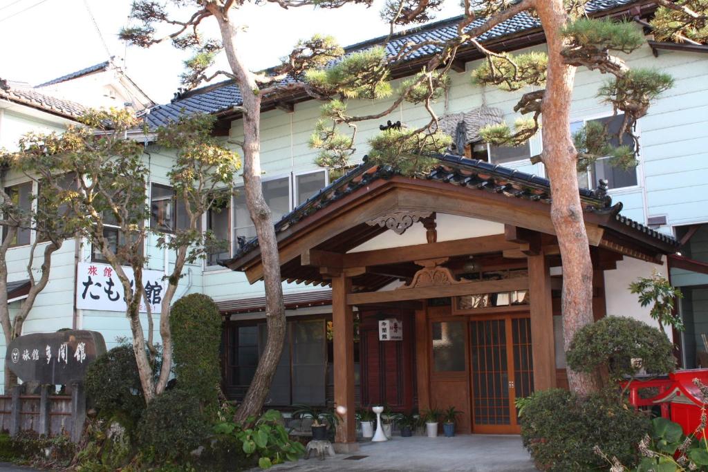 鹤冈市多闻馆酒店的屋前有遮阳篷和树木