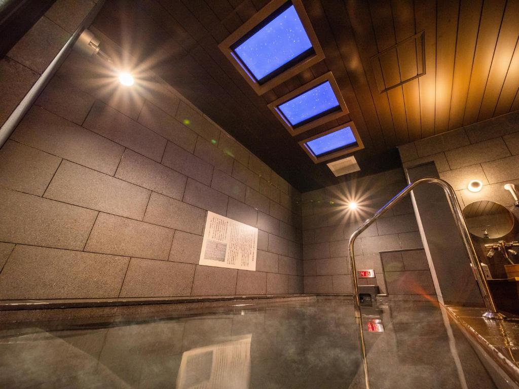 东京Super Hotel Premier Akihabara的一间带浴缸的浴室,蒸汽从浴缸中流出来