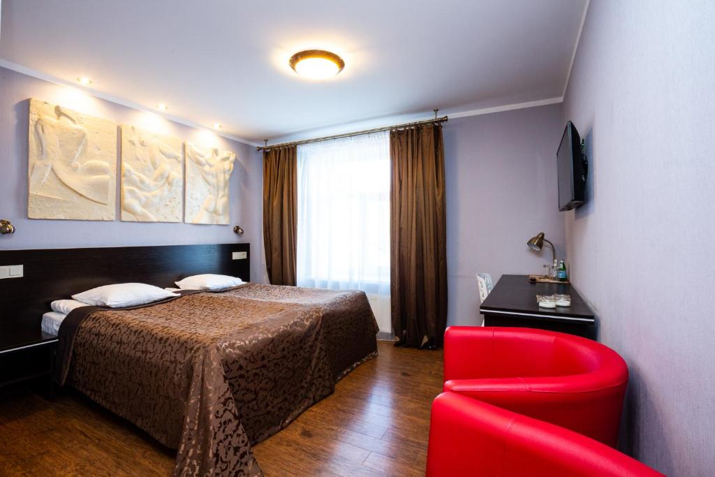 里加Primo Hotel的酒店客房,配有一张床和一张红色椅子