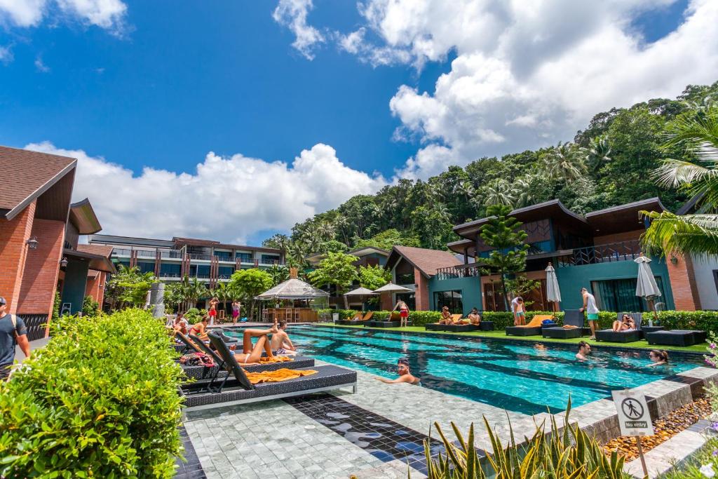 皮皮岛ChaoKoh Phi Phi Hotel and Resort- SHA Extra Plus的度假村的游泳池,人们躺在椅子上