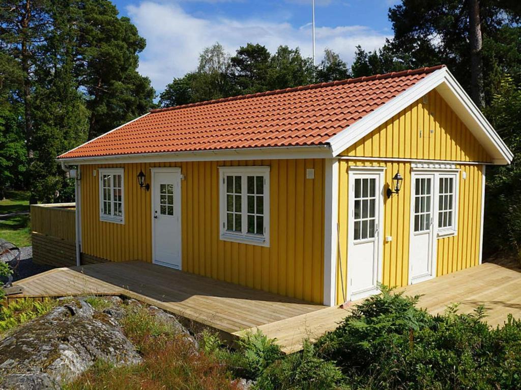 Arkösund维克博兰德两卧室度假屋 的黄色的棚子,有白色的门和木甲板