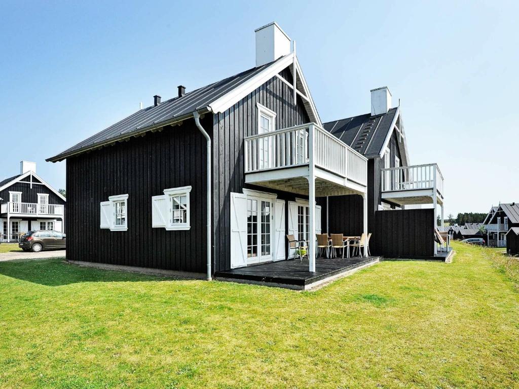 Gjern8 person holiday home in Gjern的一座黑色房子,在院子里有甲板