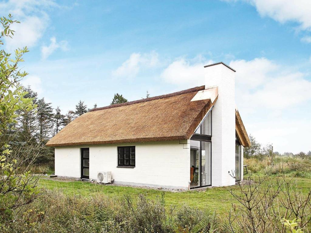 图鲁普斯特兰德7 person holiday home in Fjerritslev的一块白色房子,在田野上有一个棕色的屋顶
