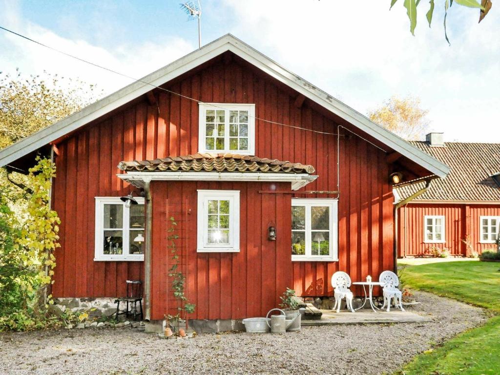 Västra Tunhem8 person holiday home in Varg n的前面的红色谷仓,有两把椅子