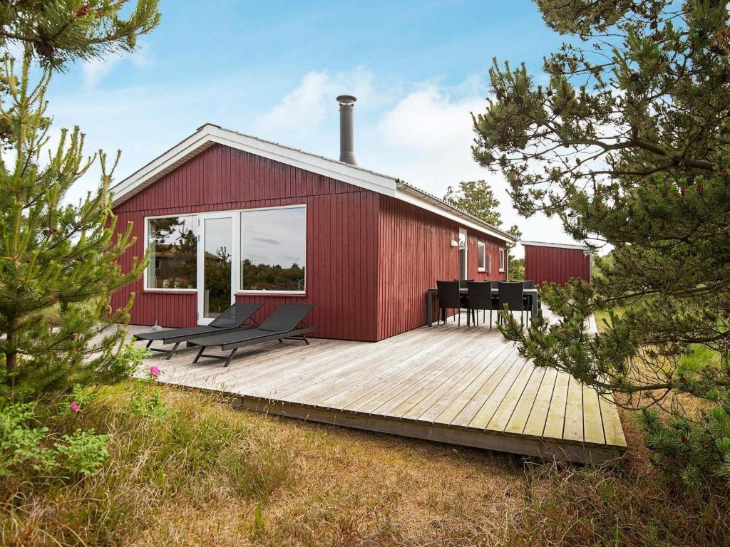 博利尔马克Three-Bedroom Holiday home in Rømø 35的一座红色的建筑,在木甲板上摆放着椅子