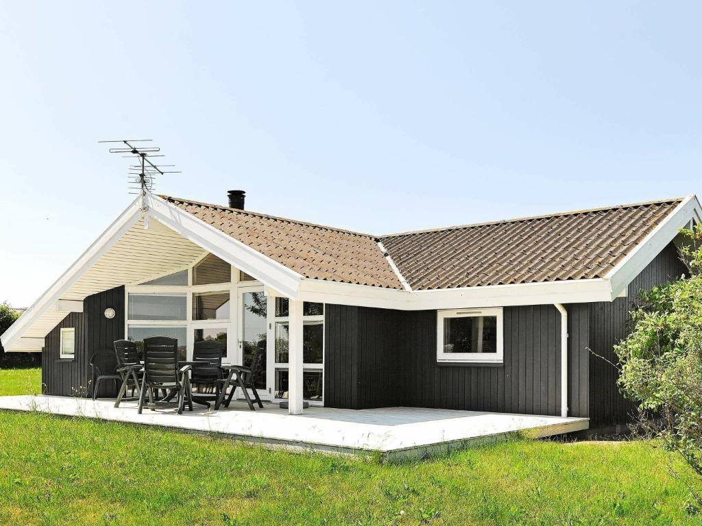 Helnæs By6 person holiday home in Ebberup的一间黑色的小房子,设有庭院和椅子