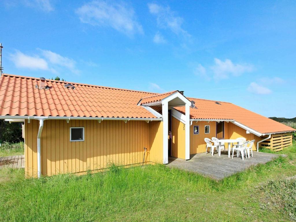 瓦伊厄斯斯特兰德8 person holiday home in Oksb l的黄色的房子,甲板上配有桌椅