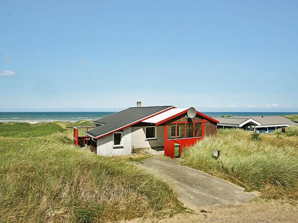 格隆霍Three-Bedroom Holiday home in Løkken 65的海滩边的红白色房子