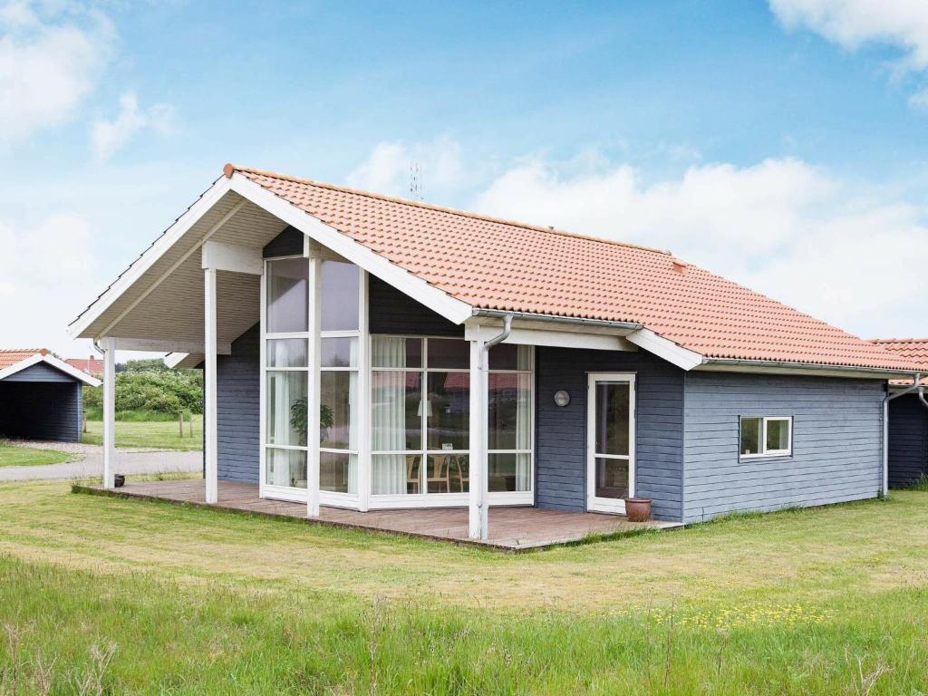法贾德嘉德8 person holiday home in Ulfborg的一间蓝色的小房子,有红色的屋顶