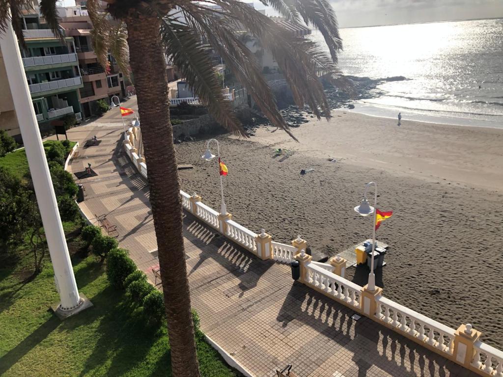 特尔德Espectacular en primera línea de la playa的享有海滩的空中景色,设有旗帜和栅栏