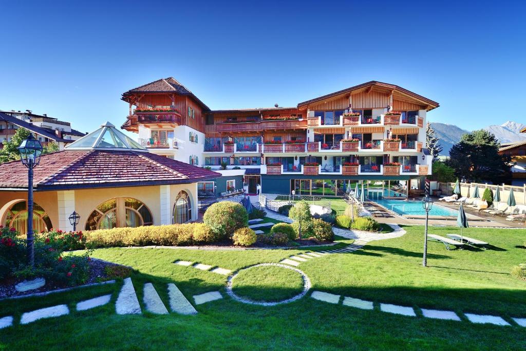 瓦尔道拉Mirabell Dolomites Hotel Luxury Ayurveda & Spa的一座带花园的大型建筑,位于度假村前