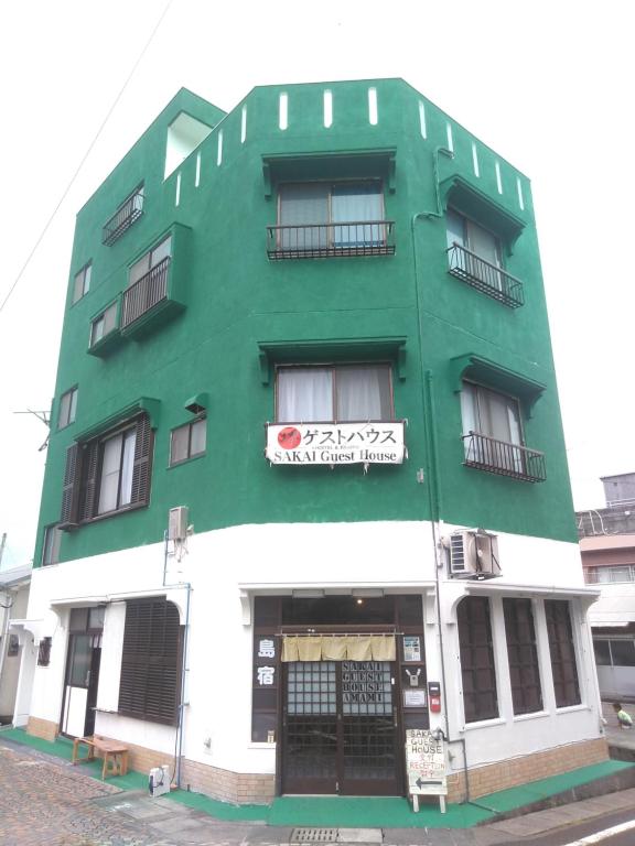 濑户内町Sakai Guest House AMAMI（堺ゲストハウス奄美）的绿色和白色的建筑,上面有标志