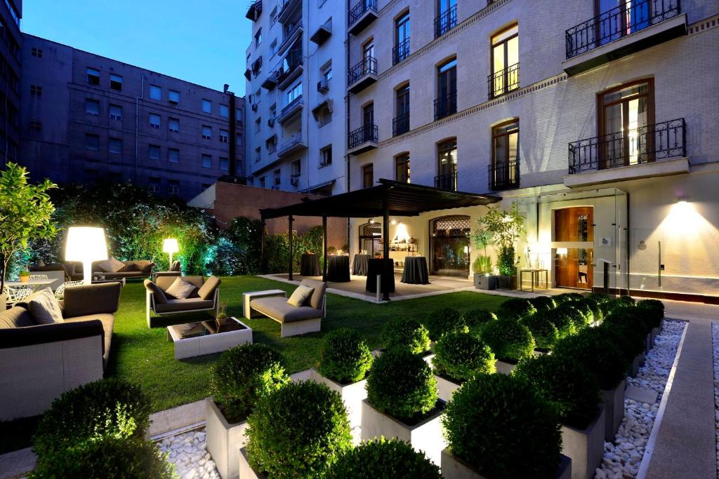马德里Hotel Único Madrid, Small Luxury Hotels的一座花园,在一座建筑前设有长沙发和灌木丛