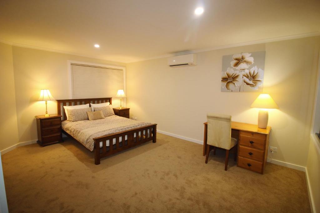 墨尔本Silver House - Melbourne Airport Accommodation的一间卧室配有一张床、一张桌子和两盏灯。