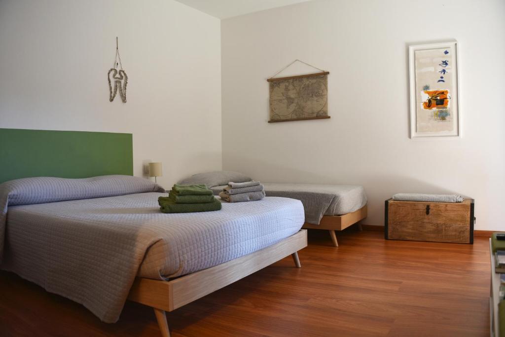 罗韦雷托B&B DEL VIAGGIATORE的配有白色墙壁和木地板的客房内的两张床