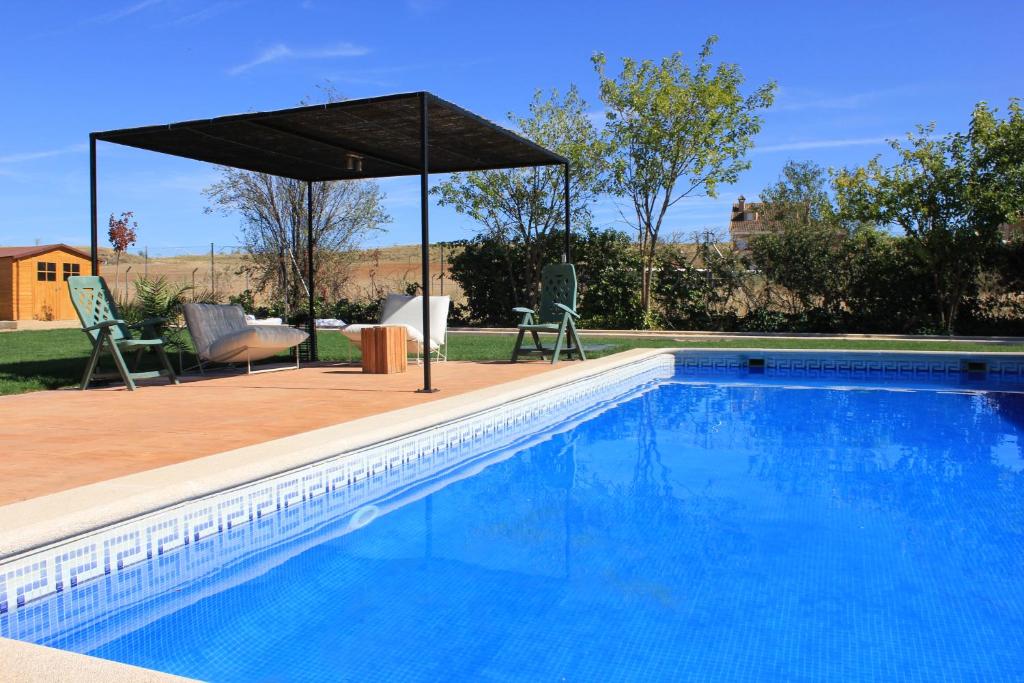 Valdetorres de JaramaFinca Paredes的一个带遮阳伞和桌椅的游泳池