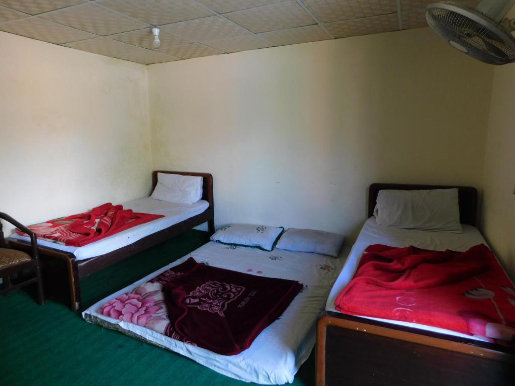 BālākotHamaliya Hotel & Restaurant的小客房内的两张床,配有红色床单
