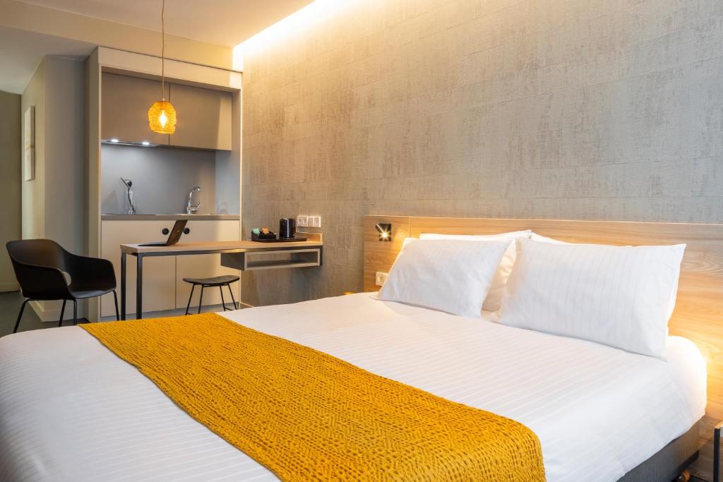 库尔布瓦Apparthotel 37 Lodge - Courbevoie La Défense的一间带白色大床的卧室和一间厨房