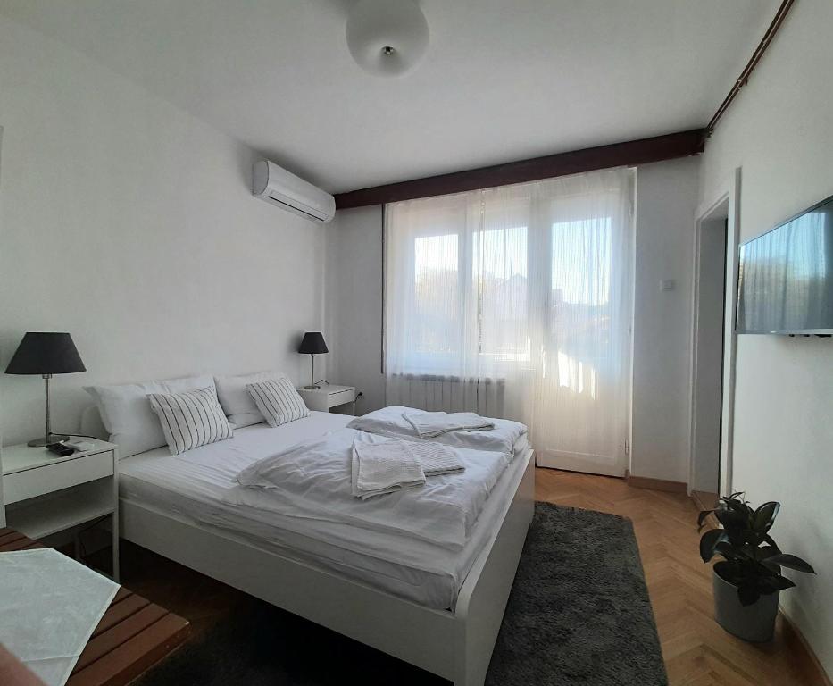 弗尔尼亚奇卡矿泉镇Vrnjci House的白色的卧室设有床和窗户