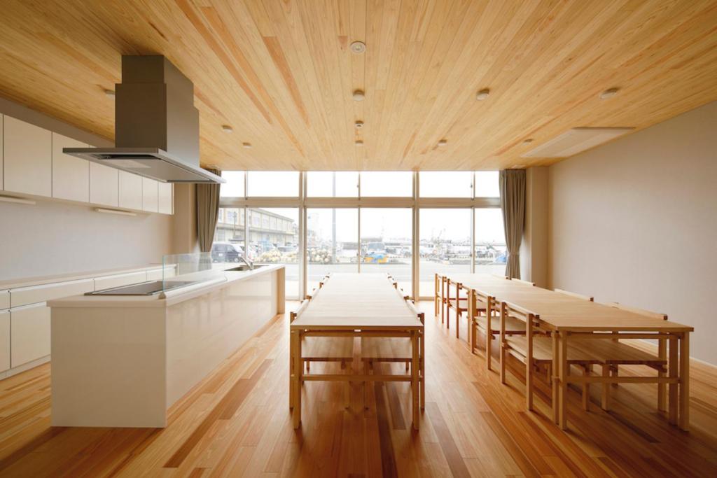 Motoshin渚泊魚津丸的厨房设有木制天花板和桌子以及大窗户。