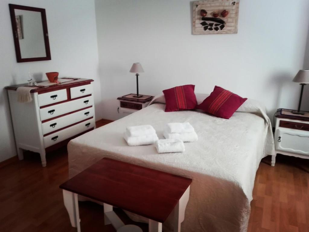 卡法亚特Hostal Virgen del Rosario Cafayate的卧室配有白色床、红色枕头和梳妆台