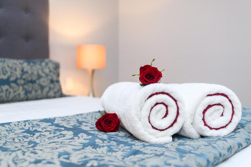 北帕默斯顿奥宾阁温泉汽车旅馆的一只毛巾动物,床上有两朵玫瑰