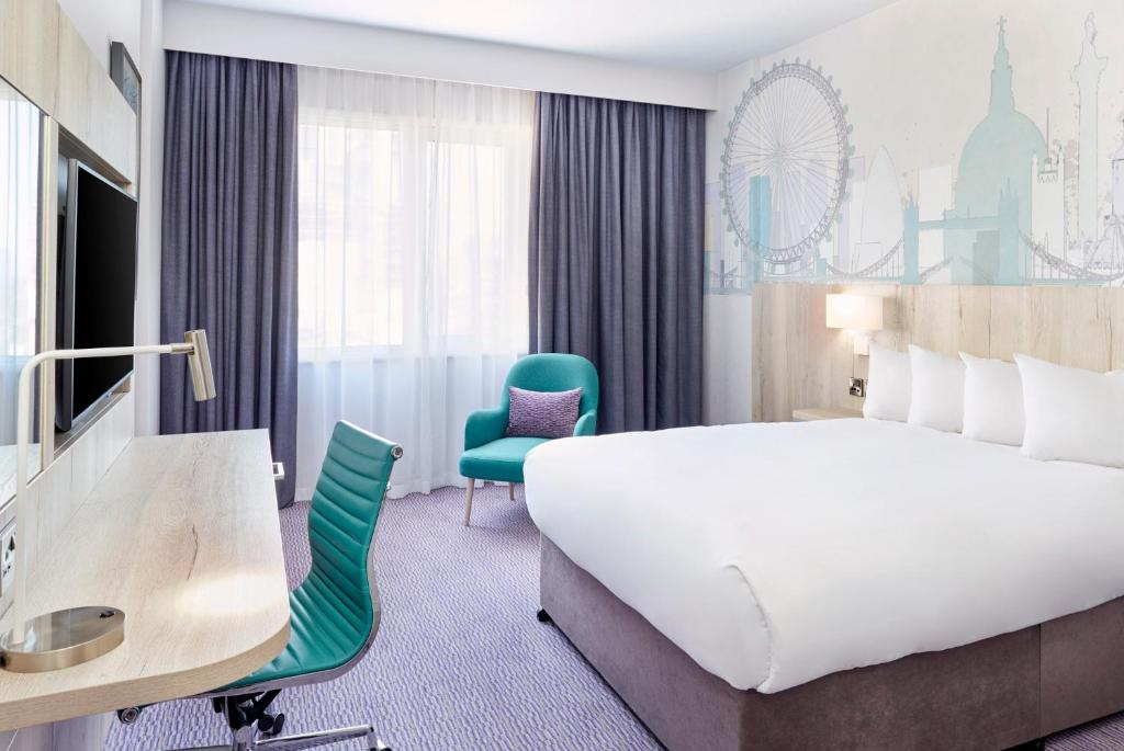 克罗伊登Leonardo Hotel London Croydon - formerly Jurys Inn的酒店客房设有一张大床和一张书桌。