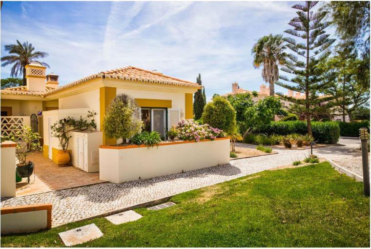 卡武埃鲁2bedroom bungalow on Gramacho Golf Resort heated shared pool的黄色的房子,前面有一个花园