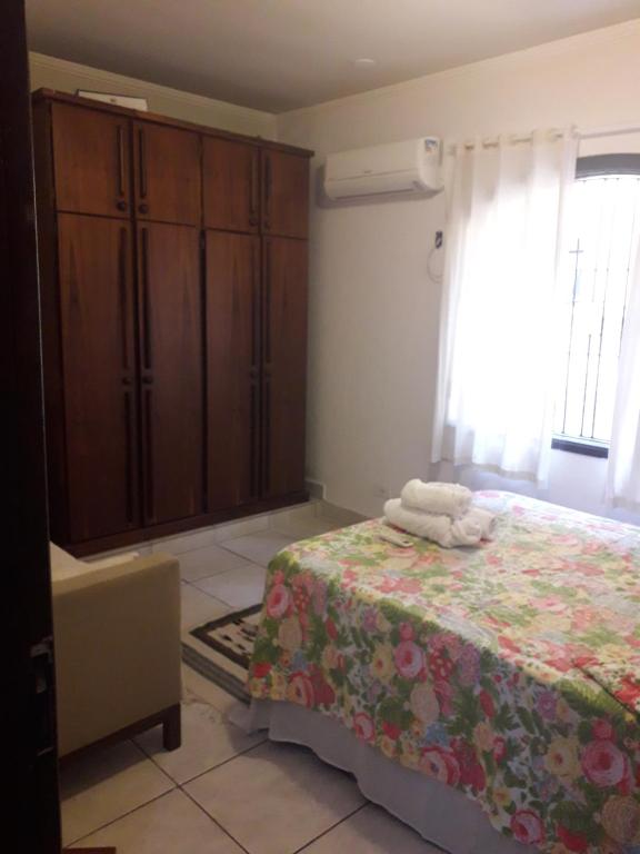 瓜鲁雅Hospedagem domiciliar的一间卧室配有一张床、梳妆台和一张床