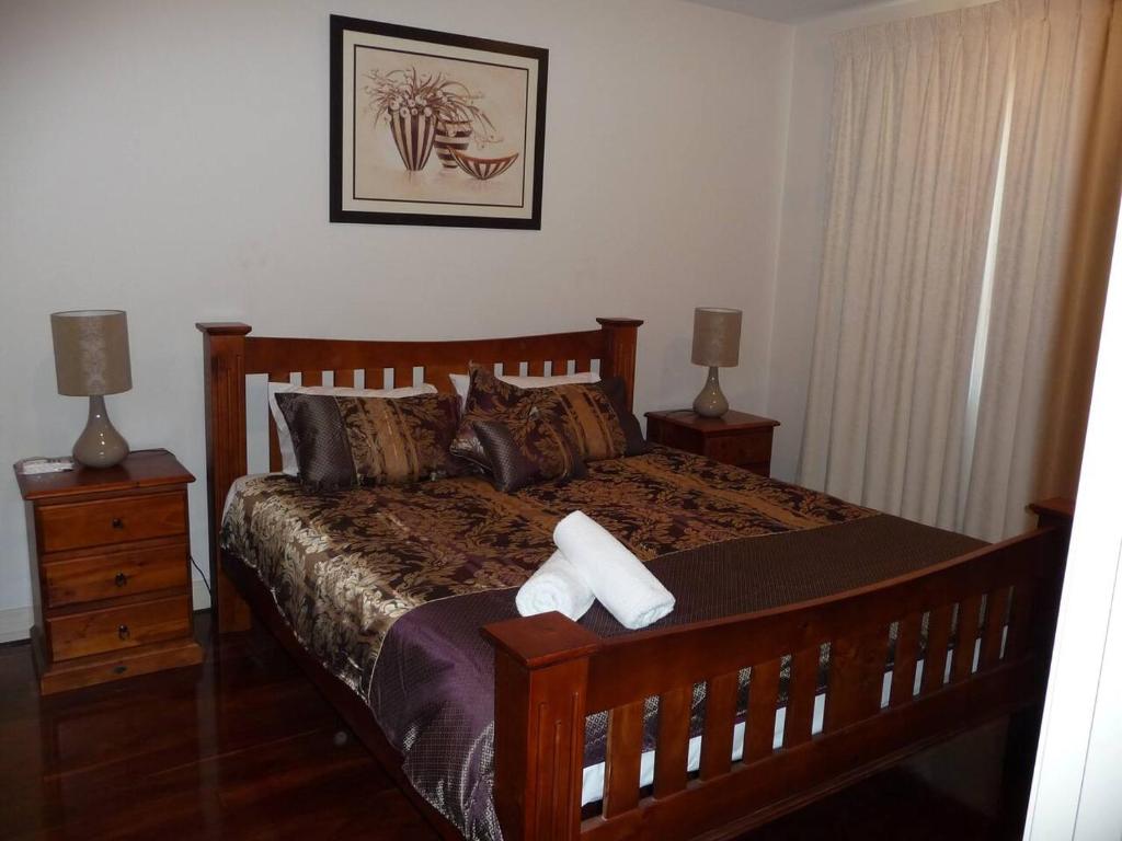阿德莱德City Getaway 3 Bedroom Adelaide's East End的一间卧室配有一张木床、两个床头柜和两盏灯。