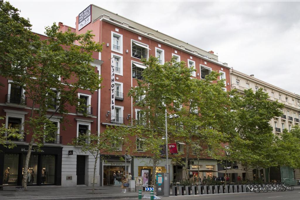 马德里ICON Embassy的城市街道上一座红砖建筑,树丛丛