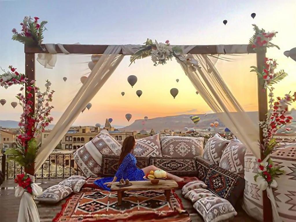 格雷梅米拉特窑洞酒店的坐在沙发上观看热气球的女人