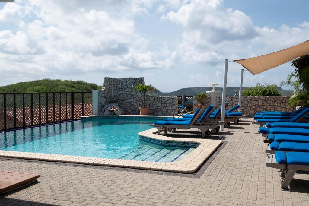 威利布罗德自然库拉索公寓式酒店的一个带蓝色椅子和一束家具的游泳池