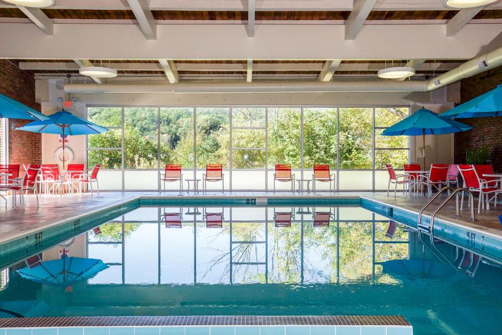 白河交界处怀特河套房酒店的一个带红色椅子和蓝色遮阳伞的游泳池