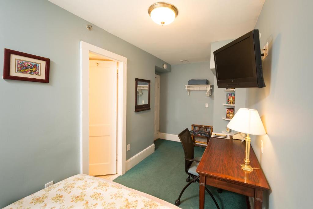 剑桥哈佛艾文豪斯酒店的一间卧室配有书桌,墙上配有电视
