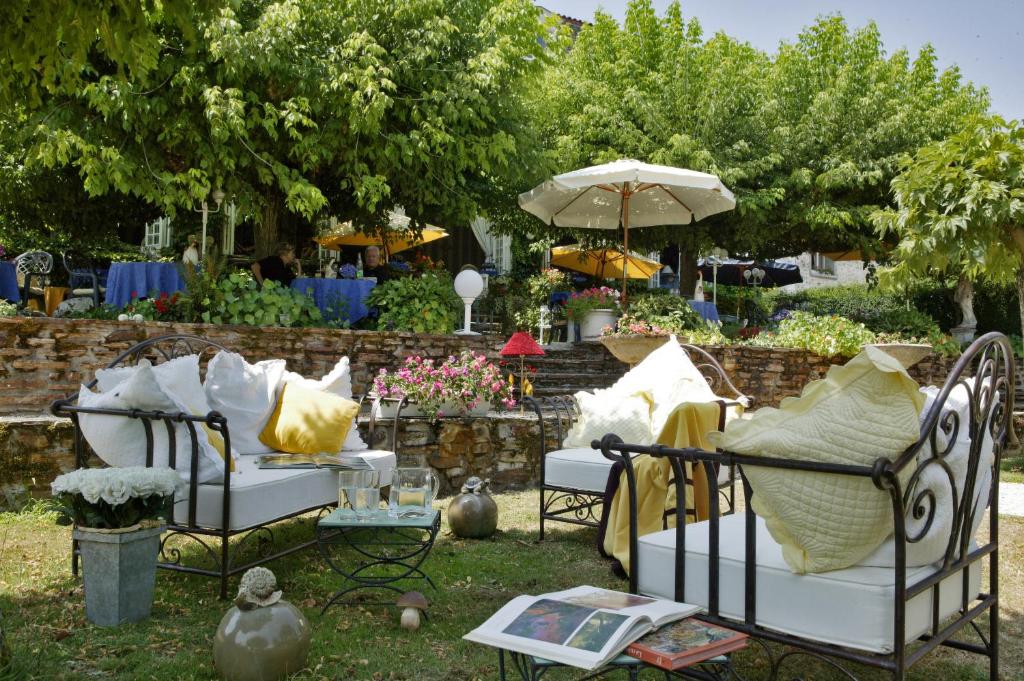 Saint-Saud-Lacoussière圣雅克酒店的一组椅子,配有枕头和雨伞
