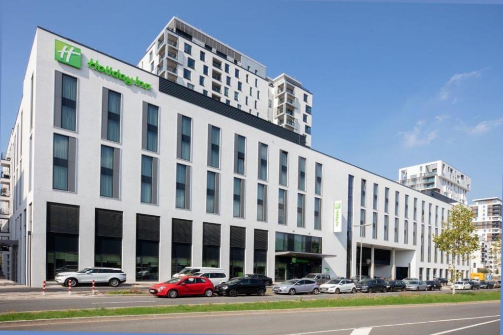 杜塞尔多夫Holiday Inn Düsseldorf City – Toulouser Allee, an IHG Hotel的白色的建筑,有汽车停在停车场
