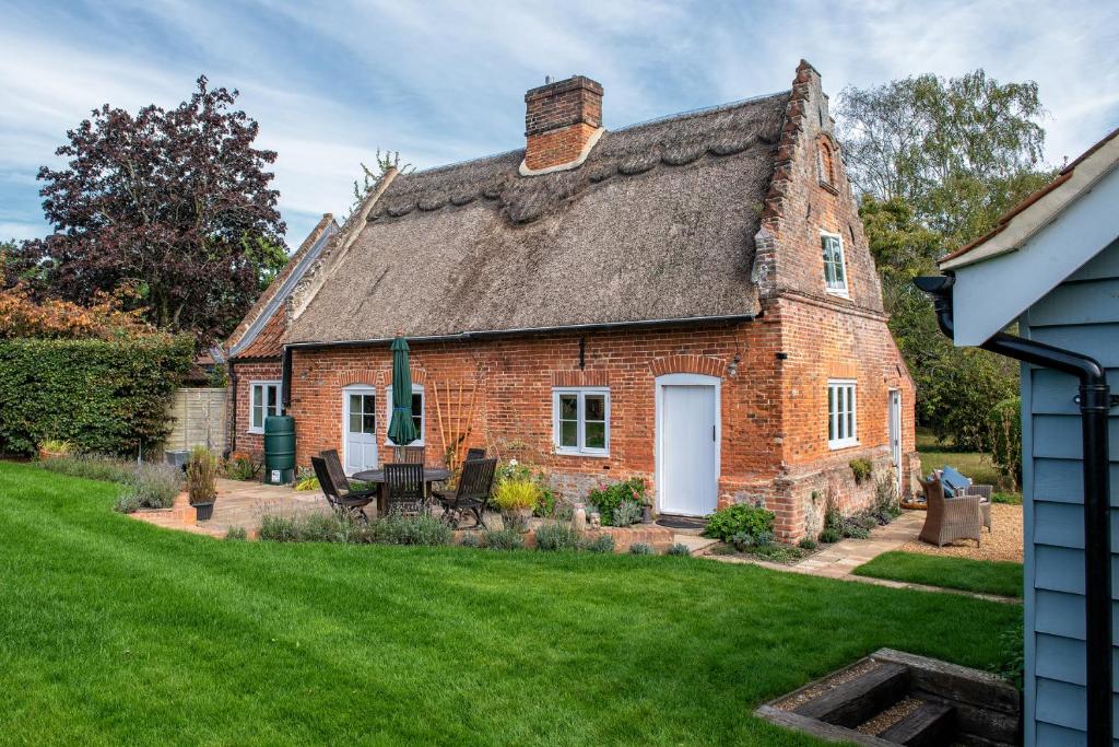 诺里奇Thatch Cottage - luxury Norfolk Hideaway的一座带草地庭院的老砖屋