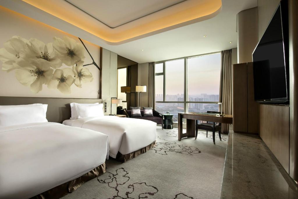 长沙长沙凯宾斯基酒店 的酒店客房设有两张床、一张桌子和一台电视。