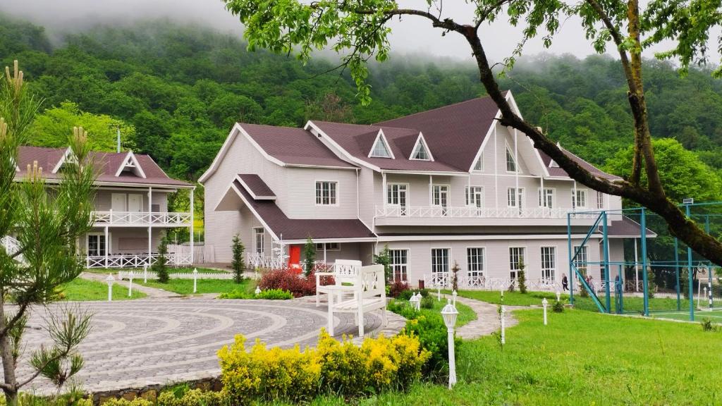 库巴Macara Village Resort的一座大型白色房子,前面设有一个游乐场