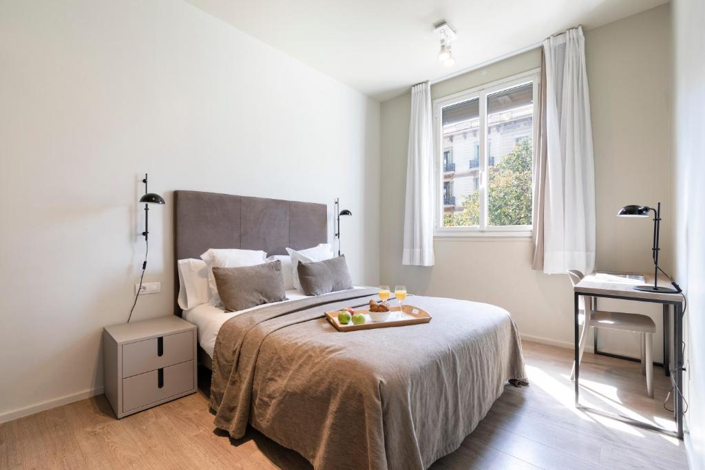 巴塞罗那阿斯帕奇亚斯兰布拉加泰罗尼亚套房公寓的一间卧室配有一张床,上面放着一个食物托盘