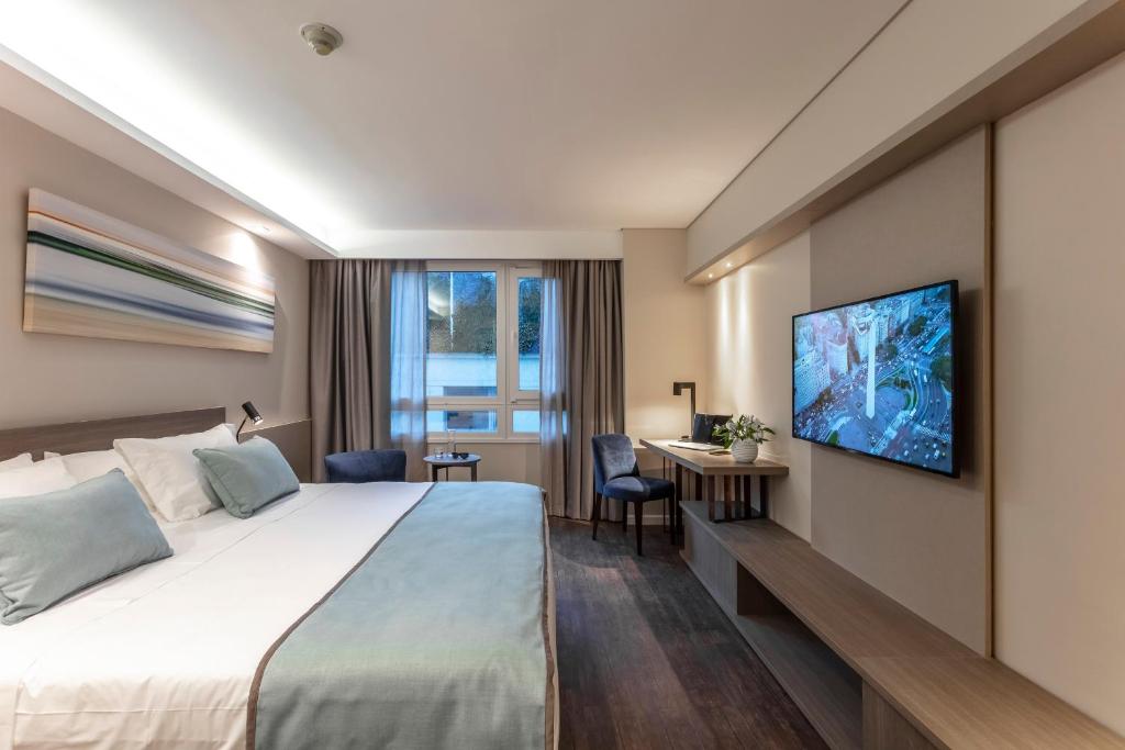 布宜诺斯艾利斯Huinid Obelisco Hotel的一间酒店客房,配有一张床和一台墙上的电视