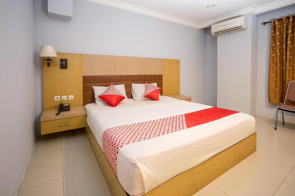 沙马林达OYO 1088 Hotel Mega Sentosa的一间卧室配有一张带红色枕头的大床