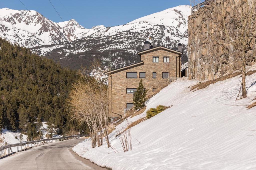 博尔德斯·代瓦里拉Pierre & Vacances Andorra Sunari Peretol的山丘上一座有雪盖的房子