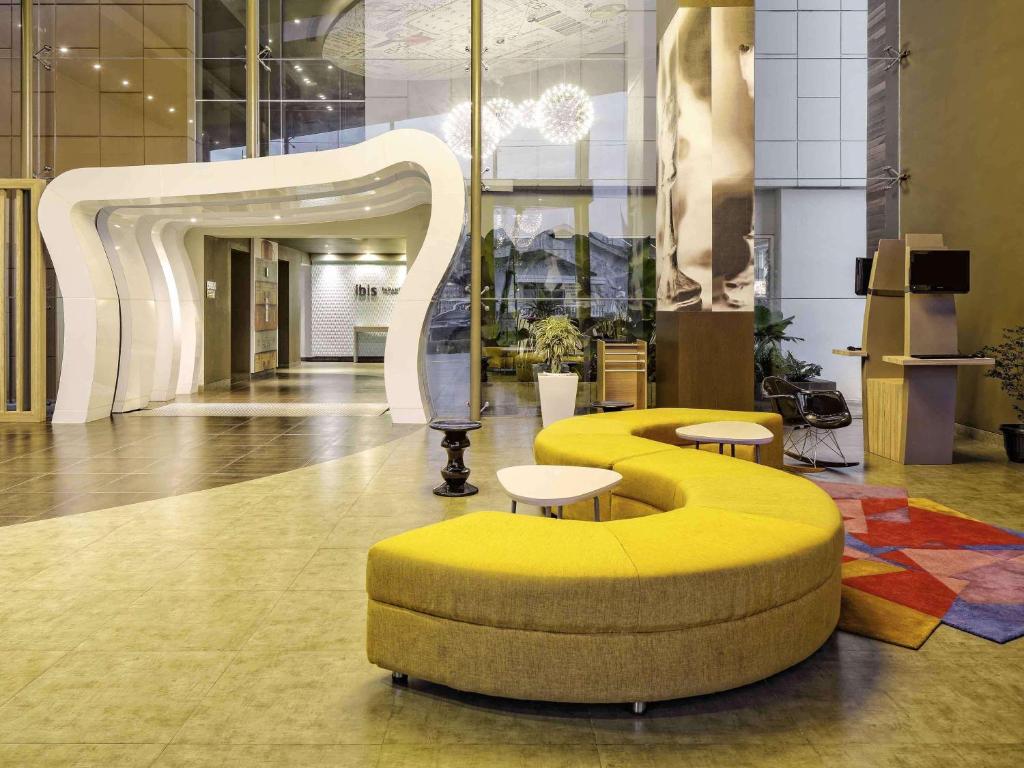 巴东巴东宜必思酒店的大楼内带黄色长凳和桌子的大堂
