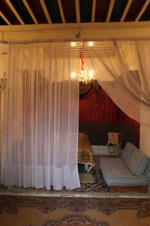 突尼斯Maison du 18ème Siècle的一间设有窗帘、一张沙发和一张床的房间