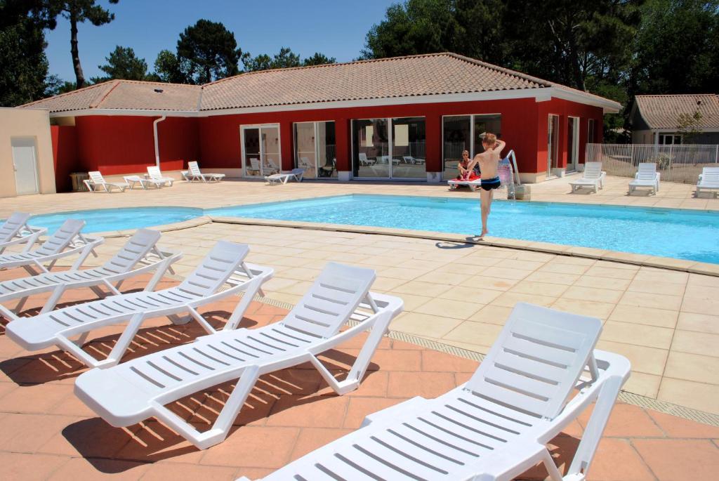 阿雷斯圣布莱斯河尼米亚酒店的一位妇女站在带躺椅的游泳池旁