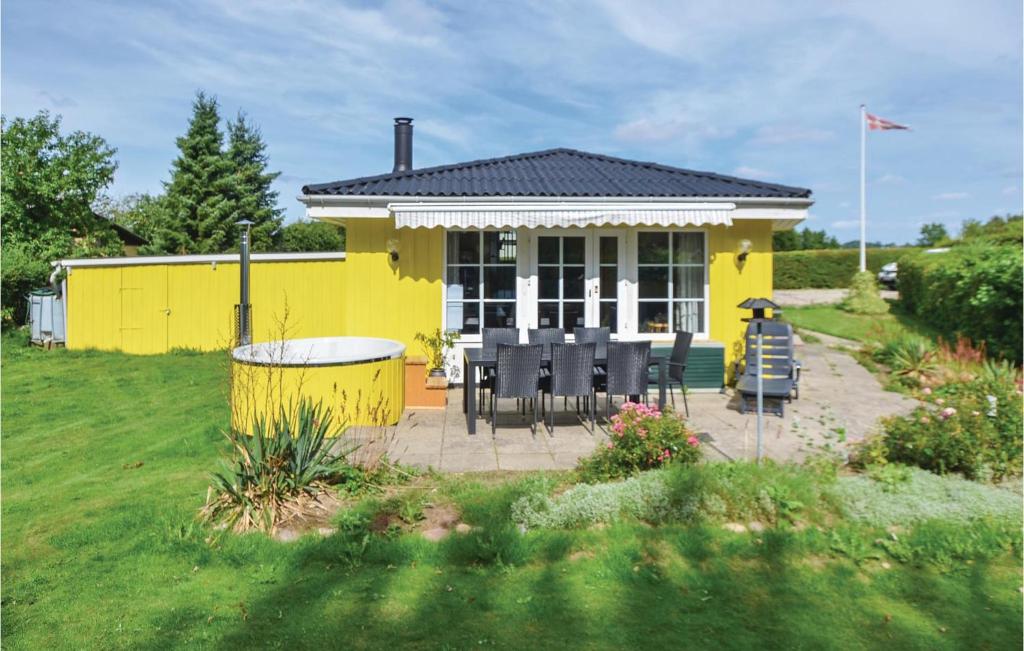 布罗艾厄Awesome Home In Broager With Wifi的院子里的黄色房子,配有桌椅