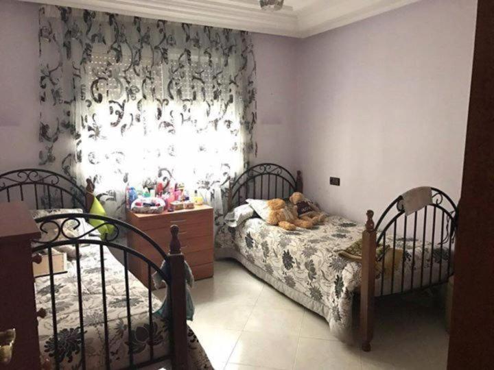 卡萨布兰卡Appartement Aznavour的一间卧室设有两张床和窗户。